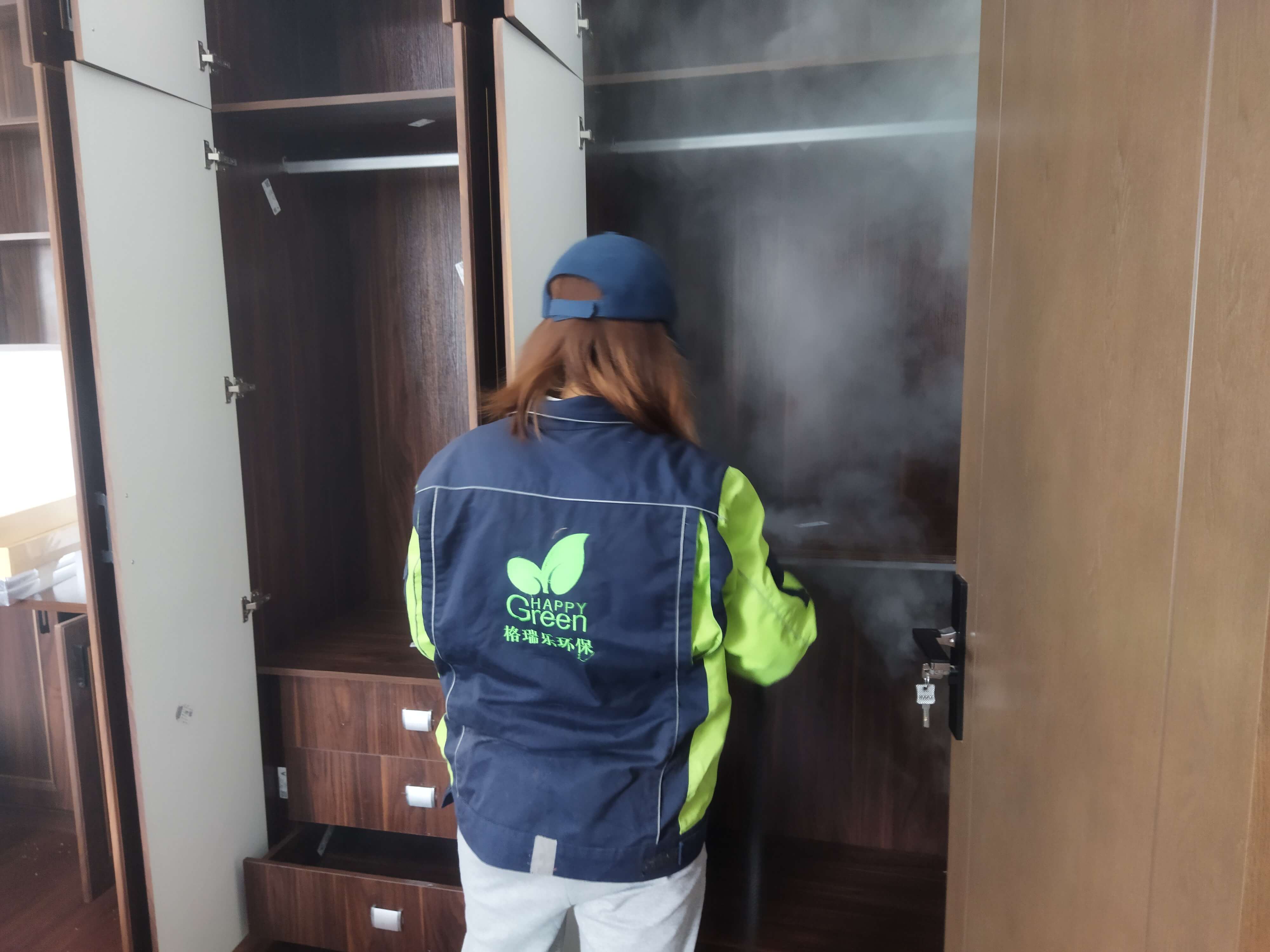 工人在新房书房，对书桌抽屉的拉手进行除甲醛的保养擦拭。