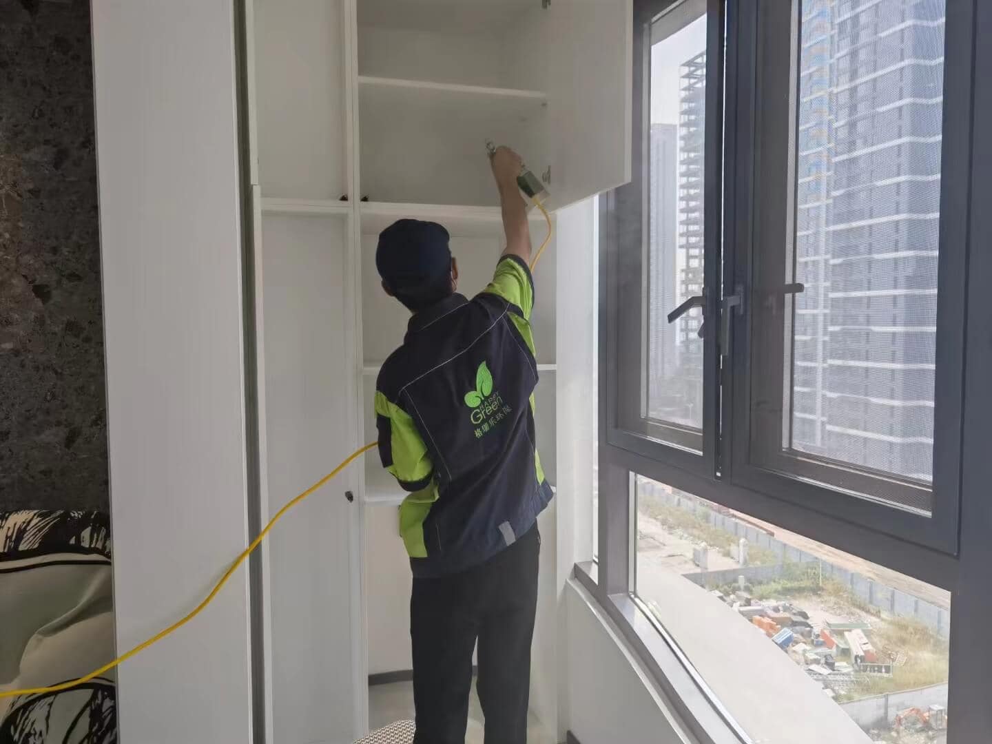 新房客厅，格瑞乐技术人员站在木质茶几旁，手持喷雾器，将除甲醛药剂均匀喷洒在茶几表面，确保每一处都被覆盖。